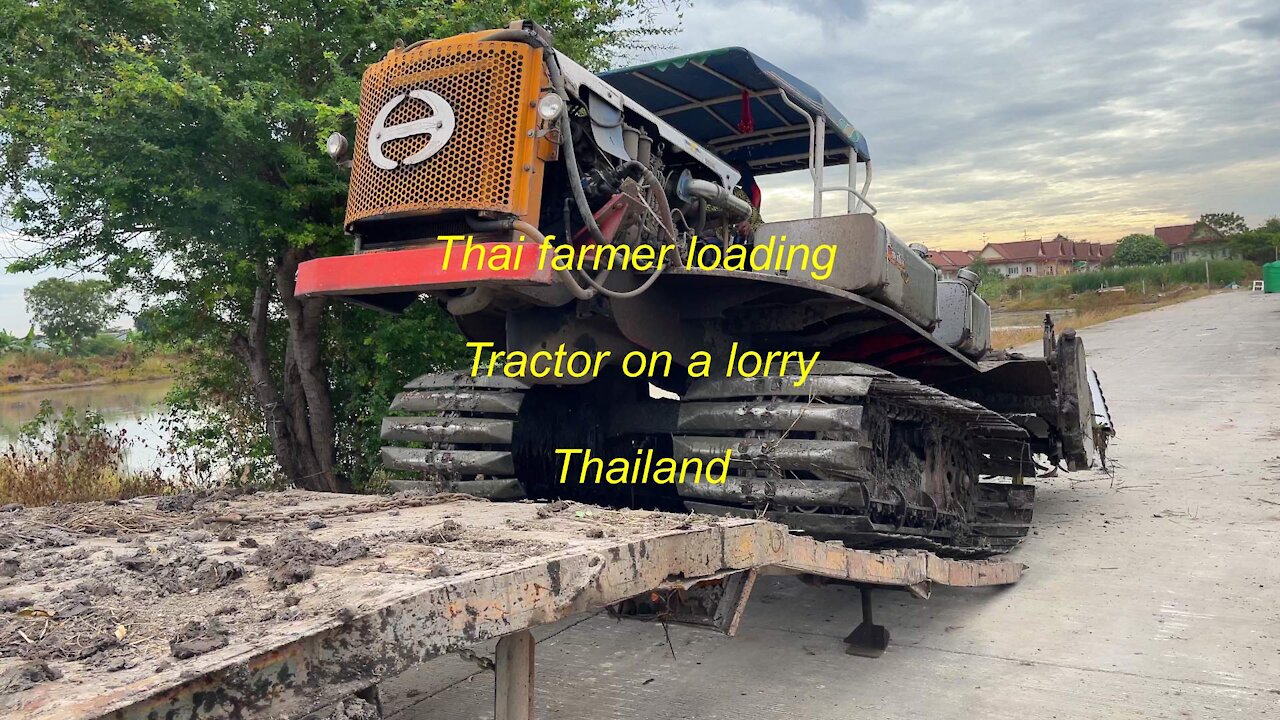 Thai farmer loading a tractor on a lorry in Thailand