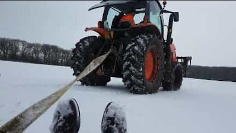 Se la spassano, trascinati sulla neve da un trattore!