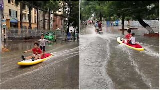 Bambini fanno surf in una strada allagata in Vietnam