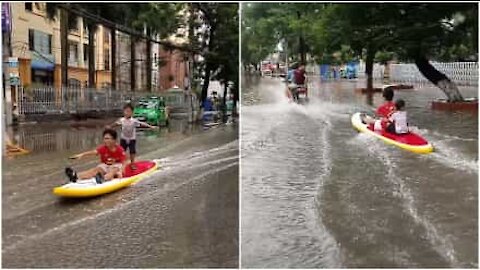 Bambini fanno surf in una strada allagata in Vietnam