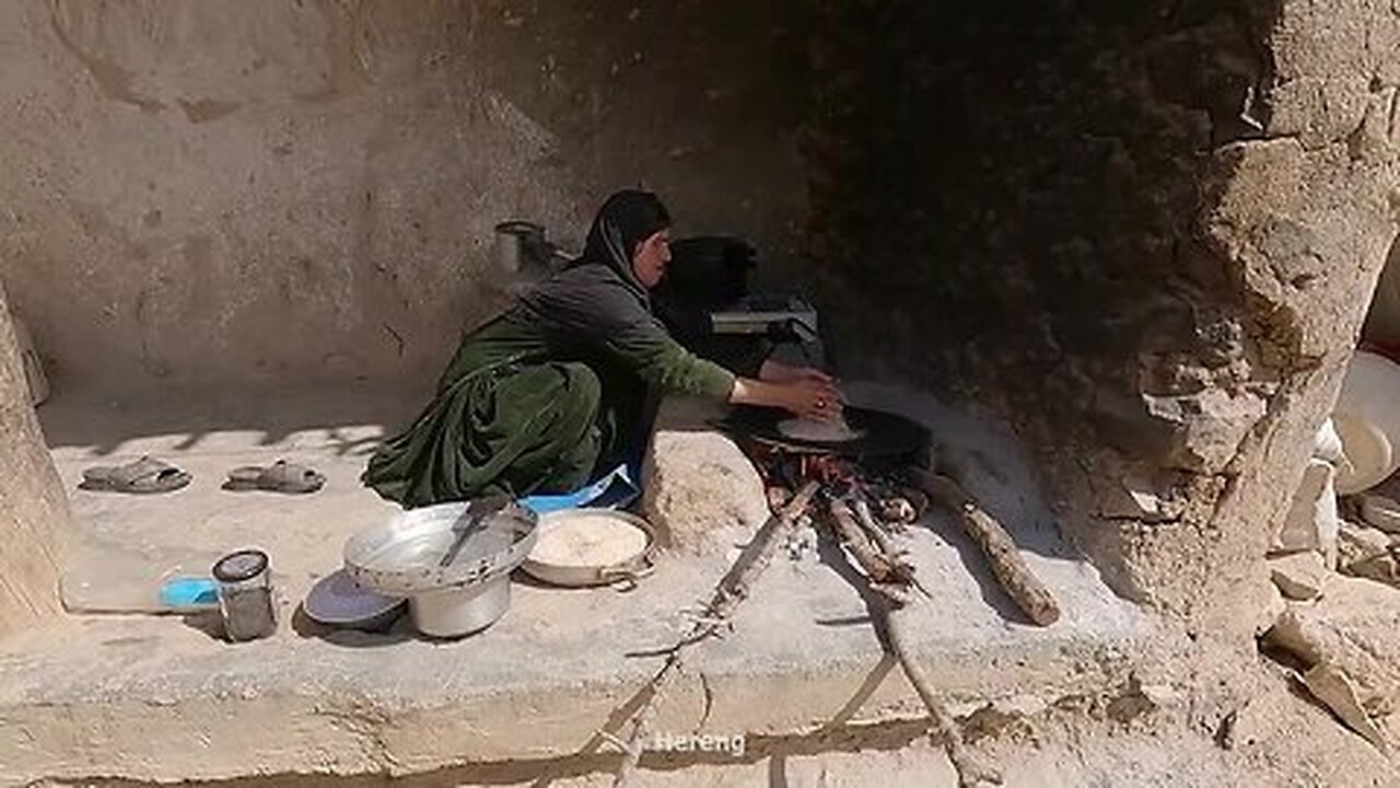 Grandma grinds wheat with a stone mill for a traditional dish