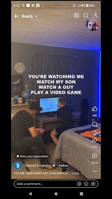 this guy is playing a video game which the son is watching. Dad watches son. They watch the video of
