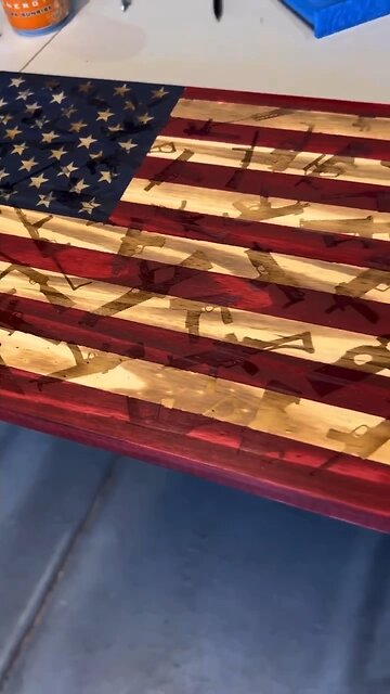 Wooden American flag with firearm background.