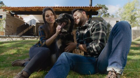 Man and woman petting their dog in a garden