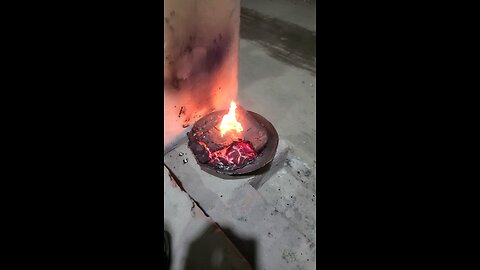 The charcoal is glowing red hot, and the flames are rising up from the top of the pot.