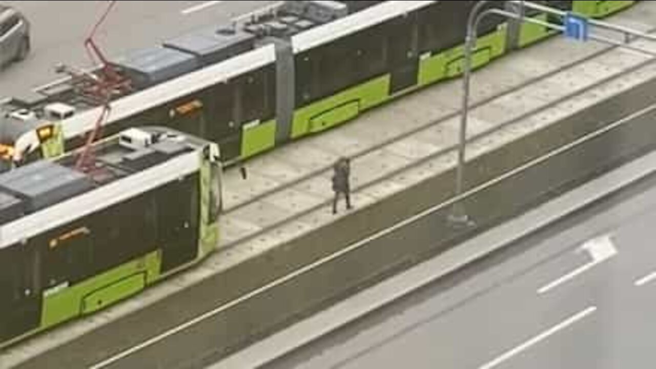 Woman with headphones in doesn't notice approaching tram