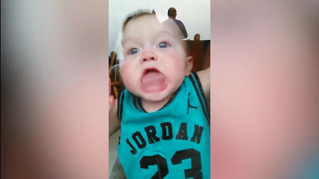 A Baby Boy Licks A Glass Window And Makes Funny Faces To His Parents