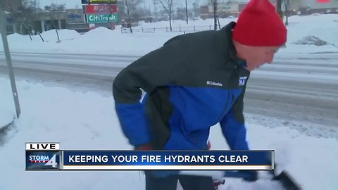 Charles Benson demonstrates how to clear out fire hyrdrants during a snow storm