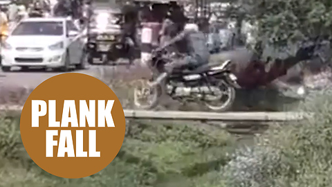 Motorbiker tries to drive across a plank footbridge only meant for people