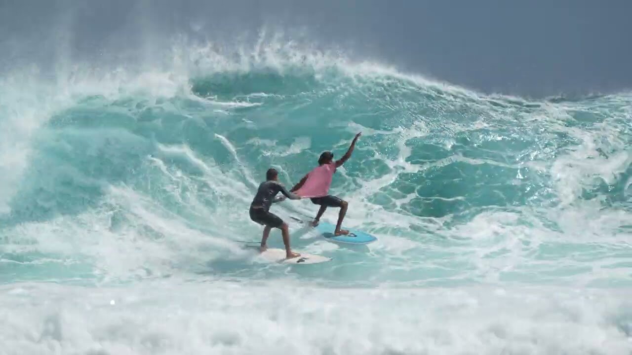 Surfer's Playful Wave Ride: Pushing Another Rider with a Smile