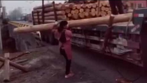 Une femme minuscule déplace un immense tronc d'arbre