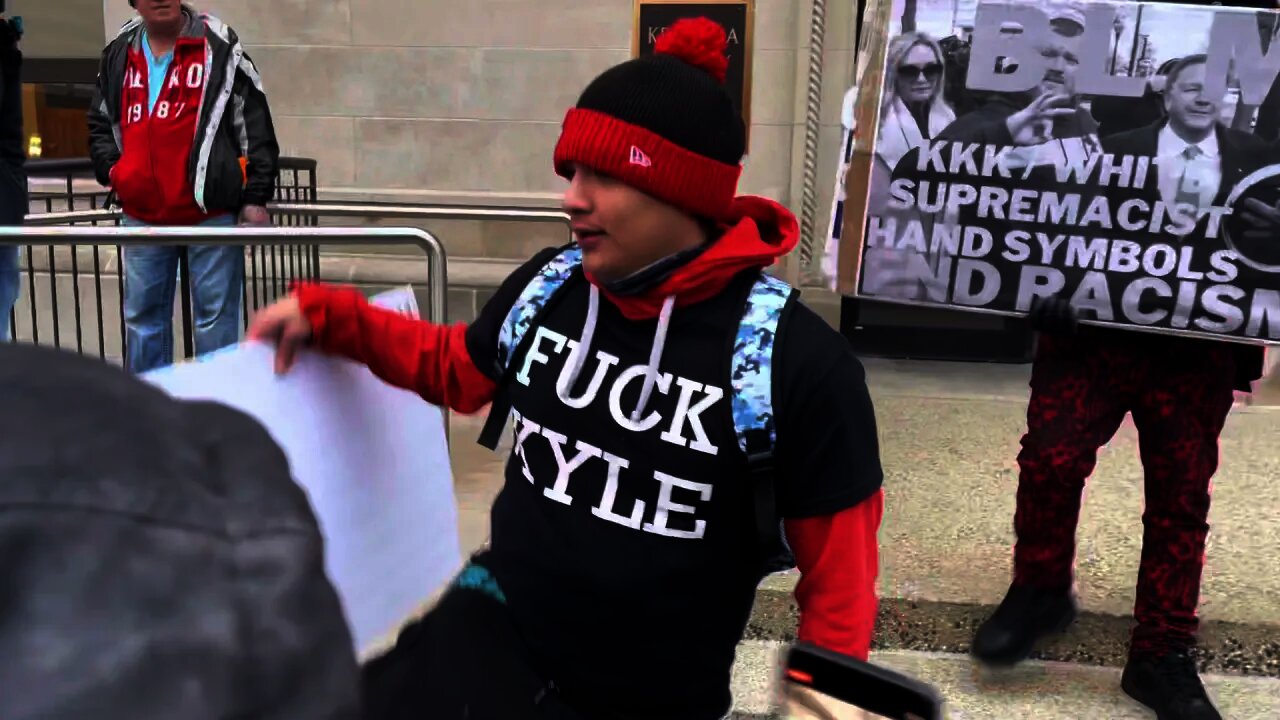 Man throwing sign at a woman. Outside Kenosha courthouse on 17 Nov 2021