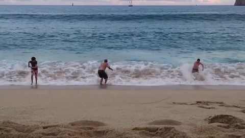 A Large Wave Knocks Down A Family On The Beach