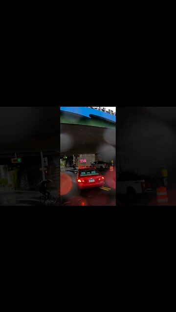 future organ donor rides against traffic in a rain storm with one hand on the handlebar