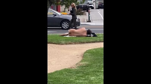 Nude homeless man lounges out on the grass in LA as women walk by