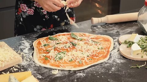 Female chef adding cheese on pizza base