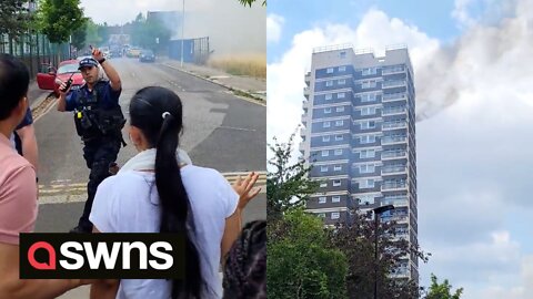 Police seen disperse bystanders after fire breaks out at top of 17-storey London tower block