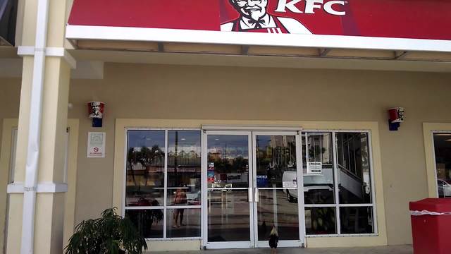 A Rooster Crows At The Door Of A KFC Restaurant