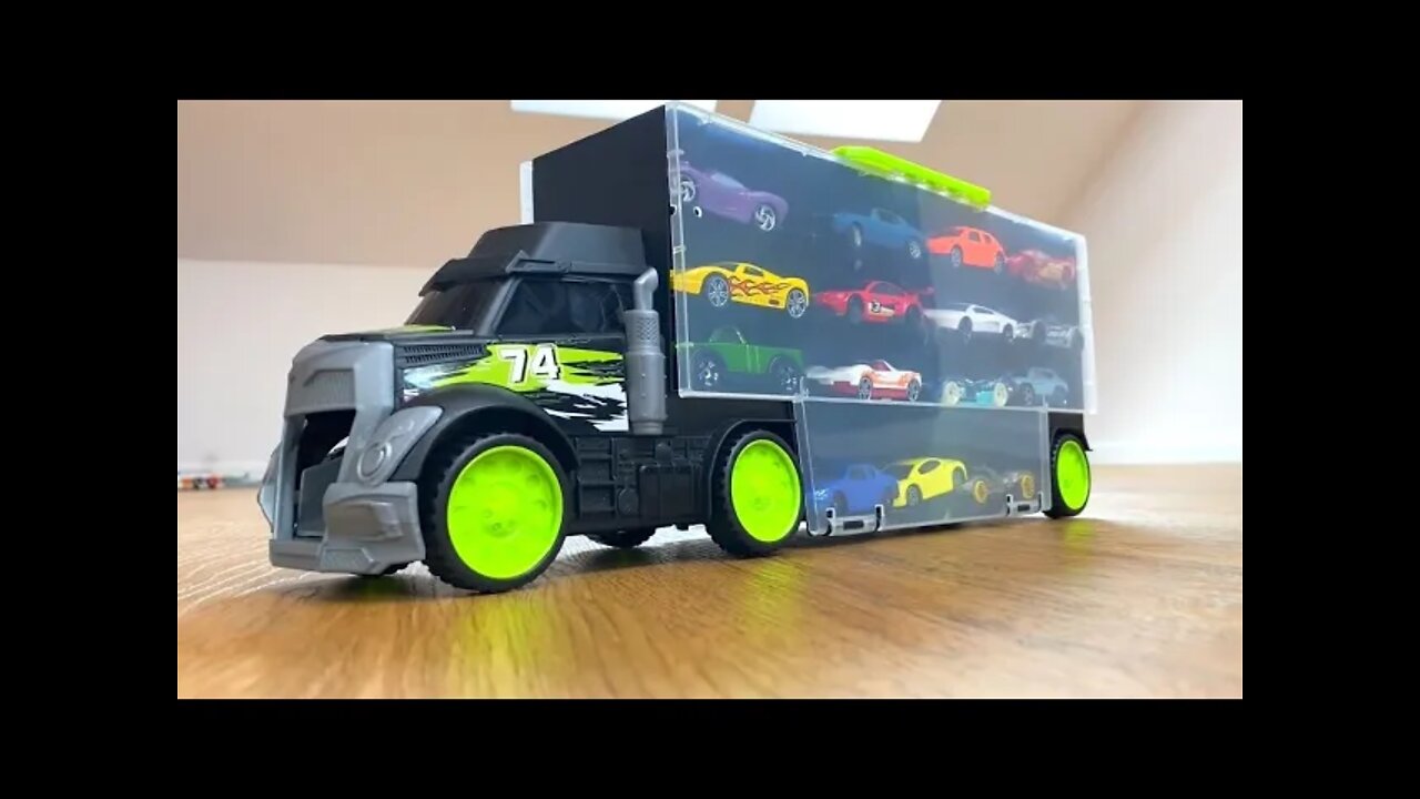 CARROS DE BRINQUEDOS DE 29 TIPOS DESLIZAM DE UM GRANDE CAMINHÃO PRETO TRANSPORTADOR