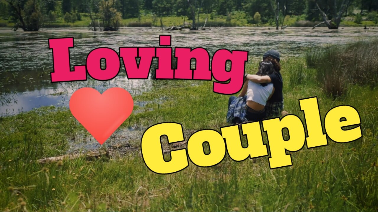 Loving couple sitting on the shore of a lake outdoors