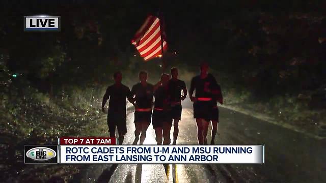 ROTC members from MSU and Michigan running game ball from MSU to UM