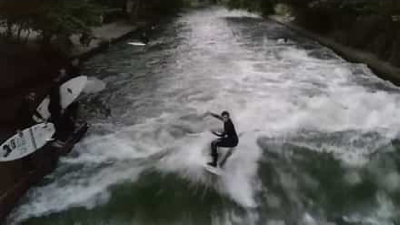 Jovem pratica surf em um rio de Munique