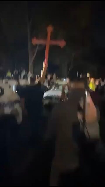 Christians hold up a cross outside the jail where a terrorist is being held for stabbing Bishop