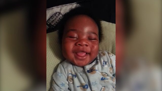 A Sleeping Baby Boy Smiles While His Mom Wakes Him Up