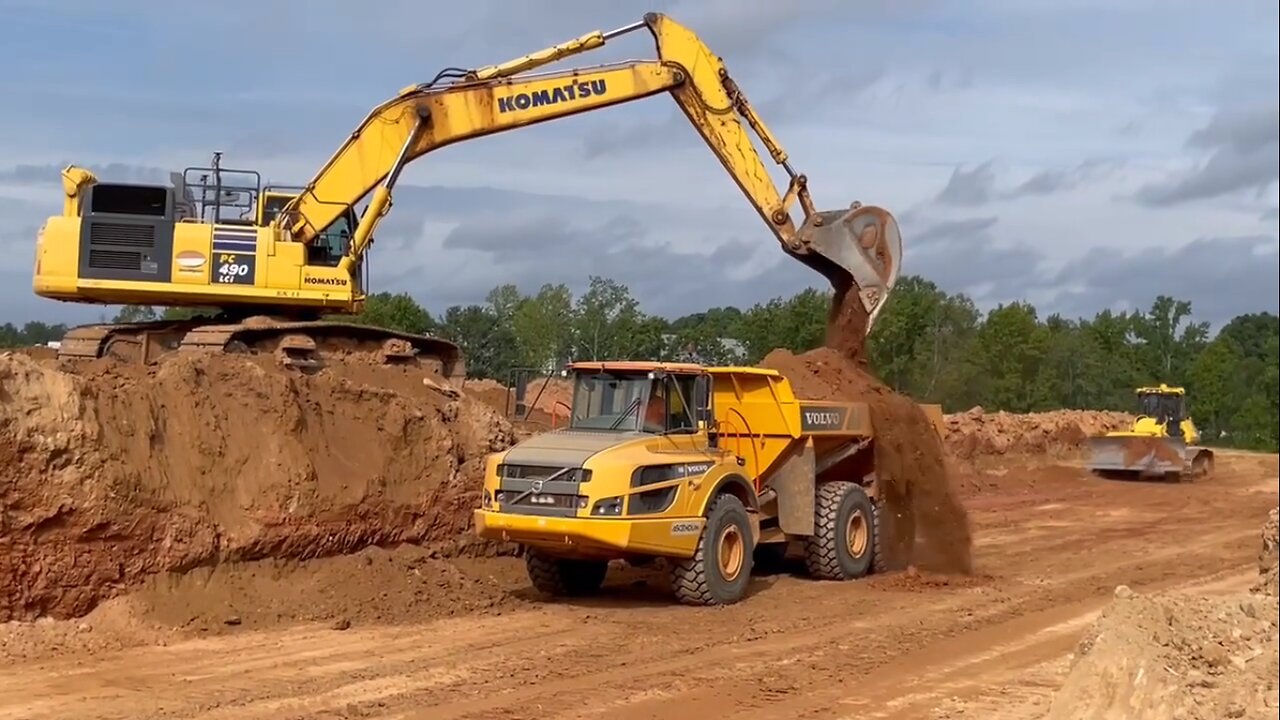 Volvo Excavator Cutting Dirt Loading Into Articulated Truck and offloading