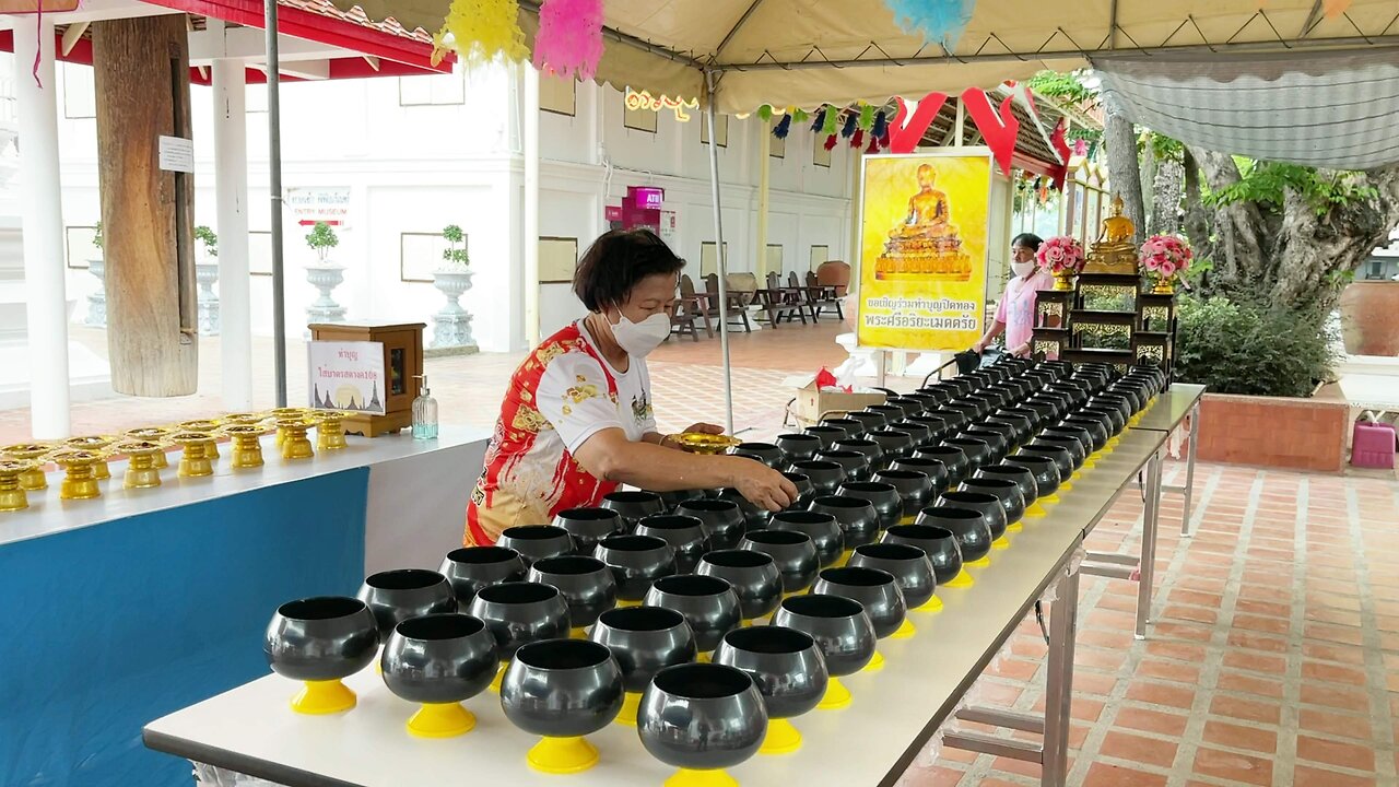 Make merit by dropping coins into the alms bowl Koh Kret Island Thailand