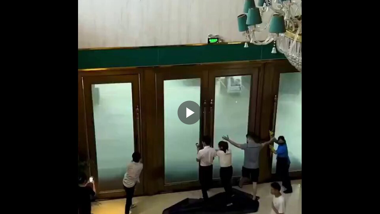 Hotel workers try to hold open doors hit by powerful gusts of wind from super typhoon.