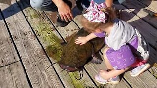 Menina pesca peixe enorme com cana de pesca de brincar