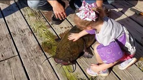 Menina pesca peixe enorme com cana de pesca de brincar