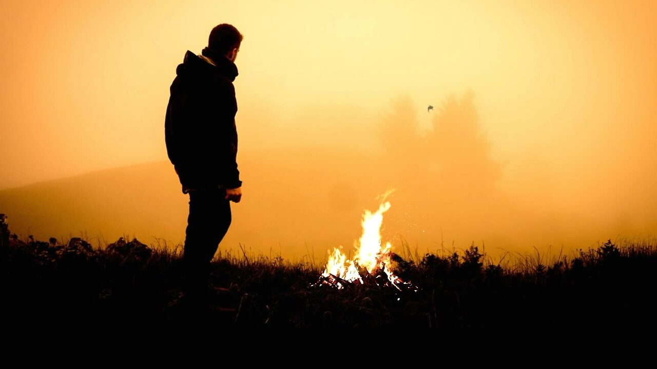 Solitary Figure by Campfire at Sunset