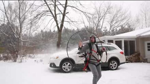 Avec un paramoteur, il déneige son véhicule!