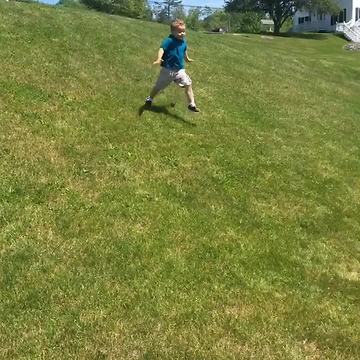 Toddler Boy Tumbles Down Grassy Hill