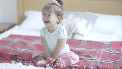 Smiling Baby Girl Sitting on Bed