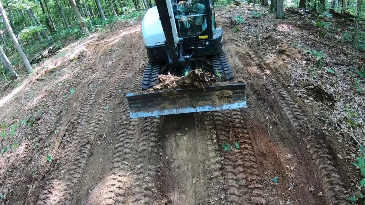 Mini excavator clearing ridgetop for new remote campsite