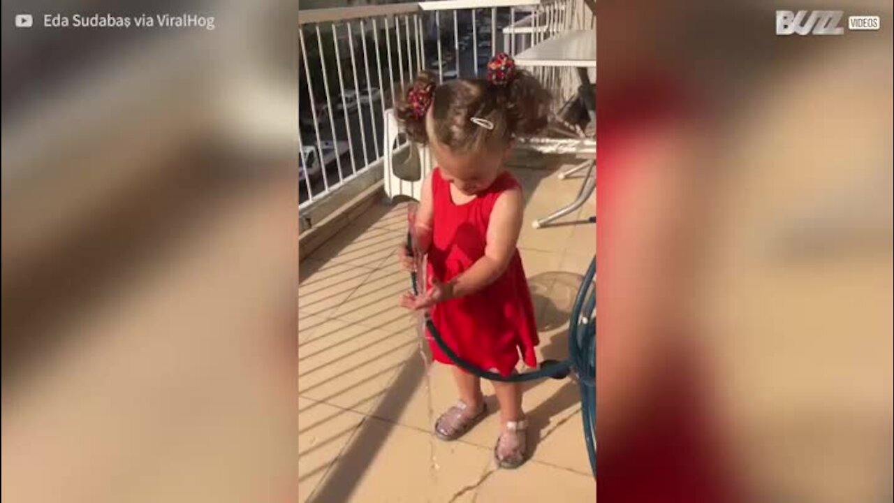 Une fillette surprise par un tuyau d'arrosage