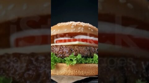 Making a Hamburger with Falling Barbecued Beef Patty, Cheddar Cheese, Sesame Bun and Vegetables