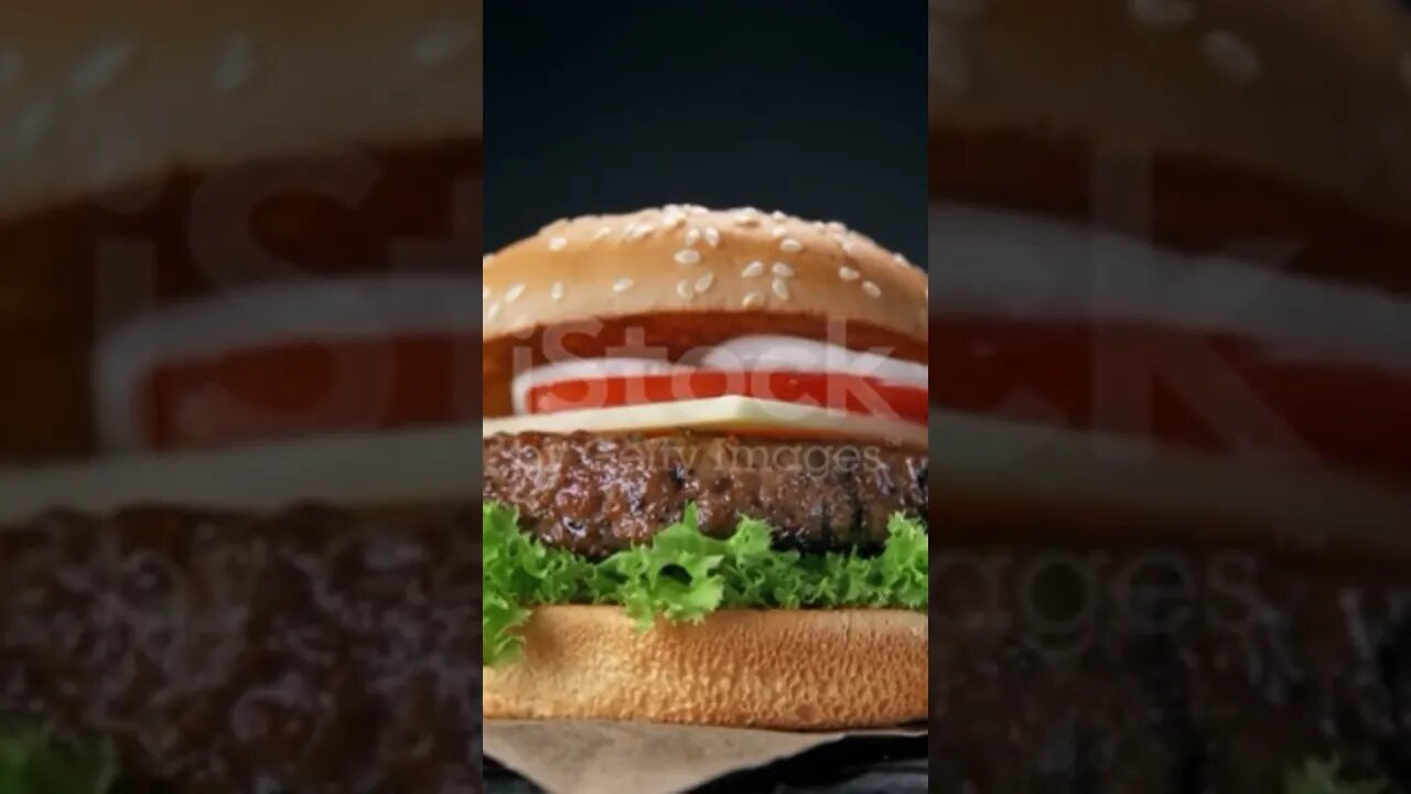 Making a Hamburger with Falling Barbecued Beef Patty, Cheddar Cheese, Sesame Bun and Vegetables