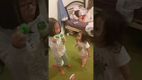 Baby girls play with bubbles while mommy chills doing phone