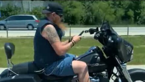 Biker uses cell phone with both hands while on freeway