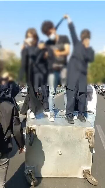 Schoolgirls stand take off their head coverings in Tehran Iran chanting "freedom, freedom, freedom"