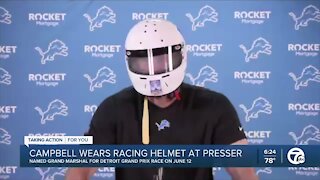 Dan Campbell wears racing helmet at press conference