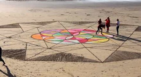 Família cria obra de arte no areal de uma praia