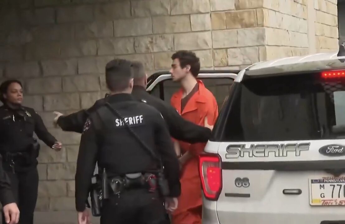 Luigi Mangione begins shouting at the media while being led from a police car to the courthouse