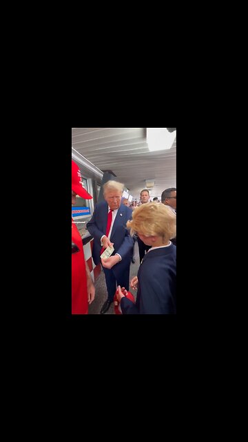 President Donald J. Trump takes out a $20 bill and signs it to give it to a young supporter.