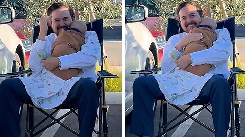 Dad rocks baby to sleep in the parking lot on a camping chair