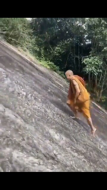 A MONK climbing with BARE FEET on the cliff that tourists climb on with the help of a rope